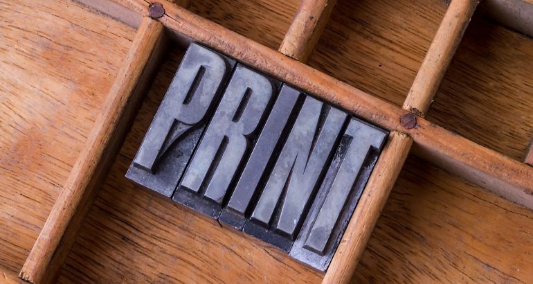 Metal letterpress in an old typesetter's drawer showing the word "PRINT"